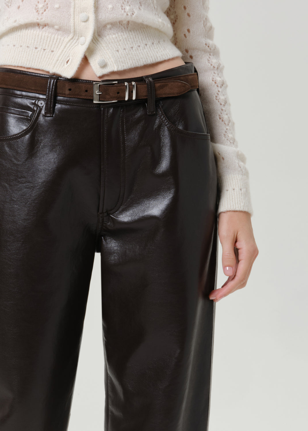 Close-up of black leather pants on a grey background.