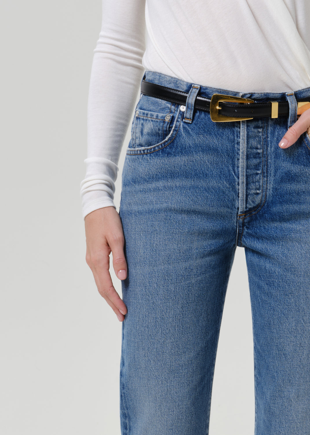 Close-up of medium blue straight leg jeans on a grey background.