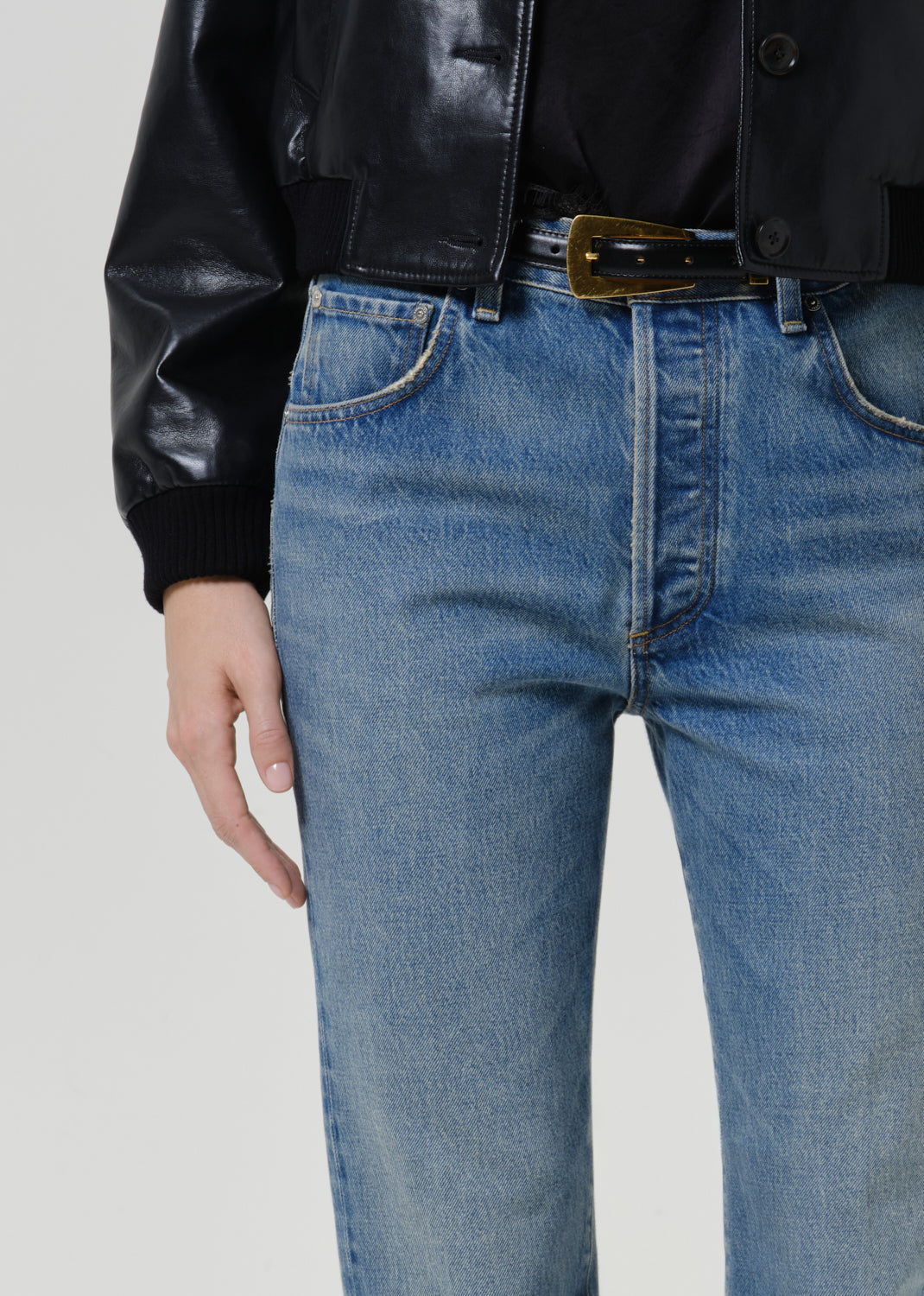 Close-up of medium blue straight leg jeans on a grey background.