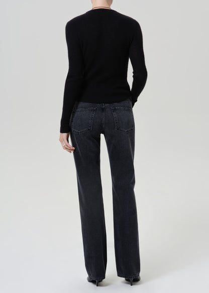 A model shown from the back wearing a black long-sleeve knit sweater and dark charcoal gray wide-leg jeans against a light gray studio background.
