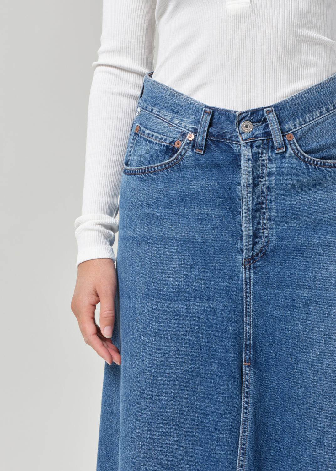 Blue denim skirt worn by a person on a plain background