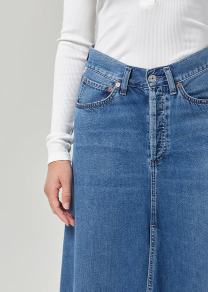 Blue denim skirt worn by a person on a plain background