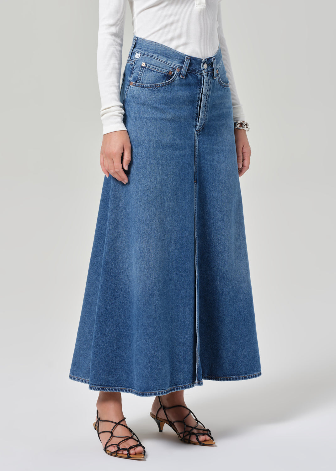 Person wearing a long blue denim skirt on a white background
