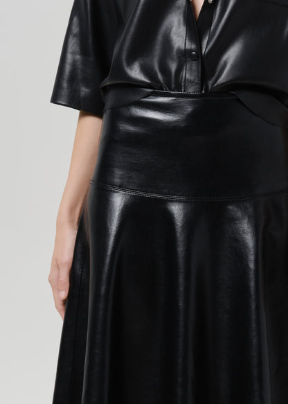 Close-up of a black leather short sleeve shirt with a black leather skirt on a grey background