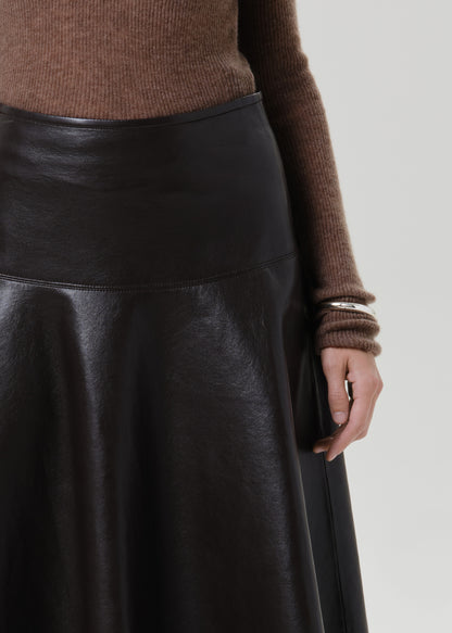 Close-up of a brown leather midi skirt with a brown long sleeve collared knit top on a grey background
