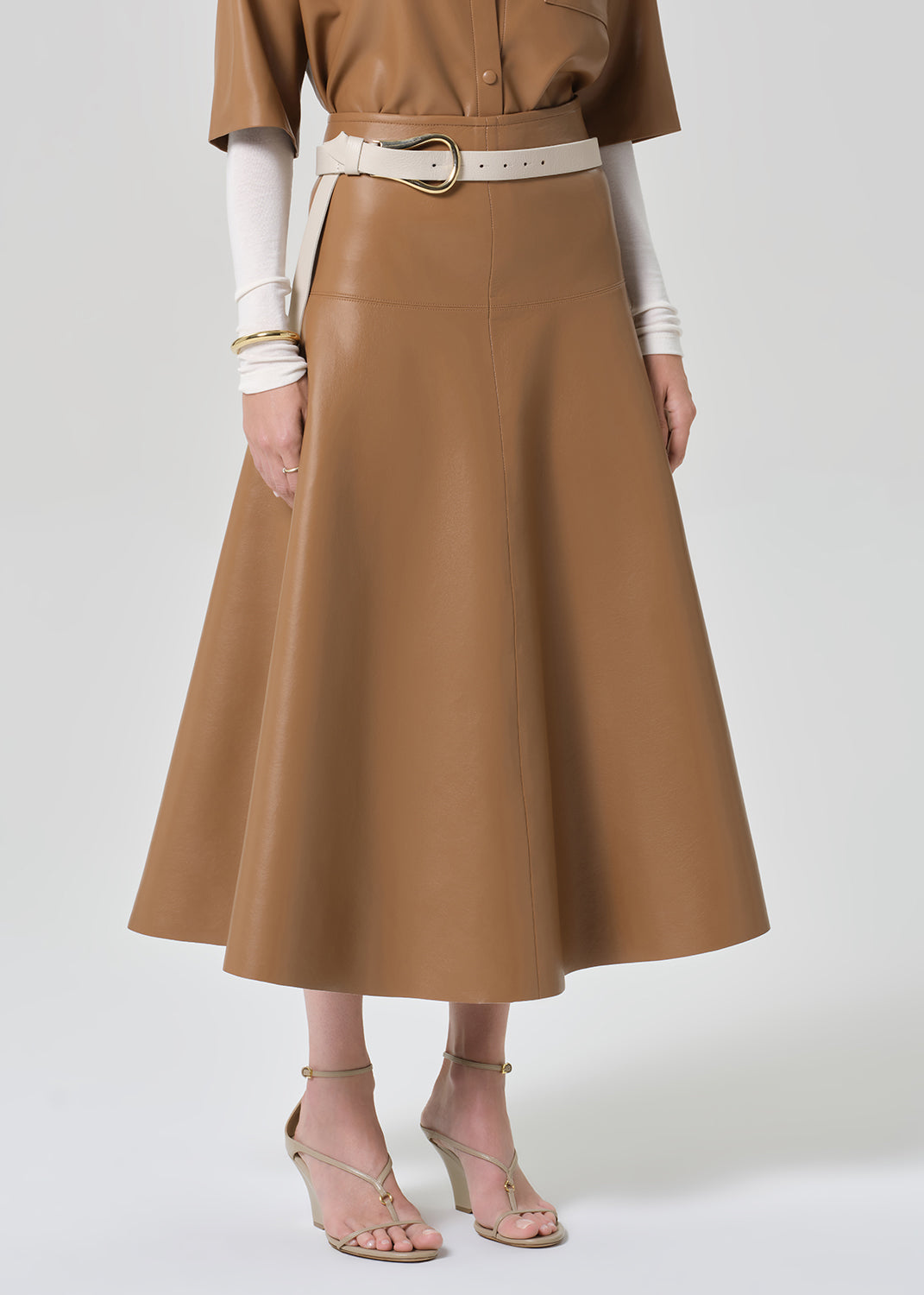 Brown leather outfit with a belt worn by a person on a grey background