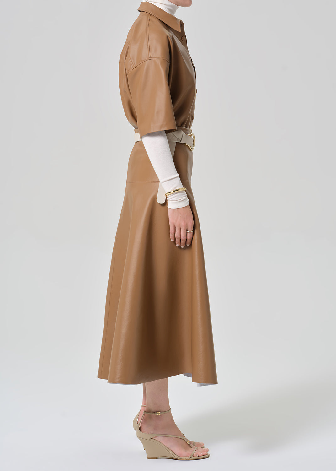 Brown leather outfit with a belt worn by a person on a grey background