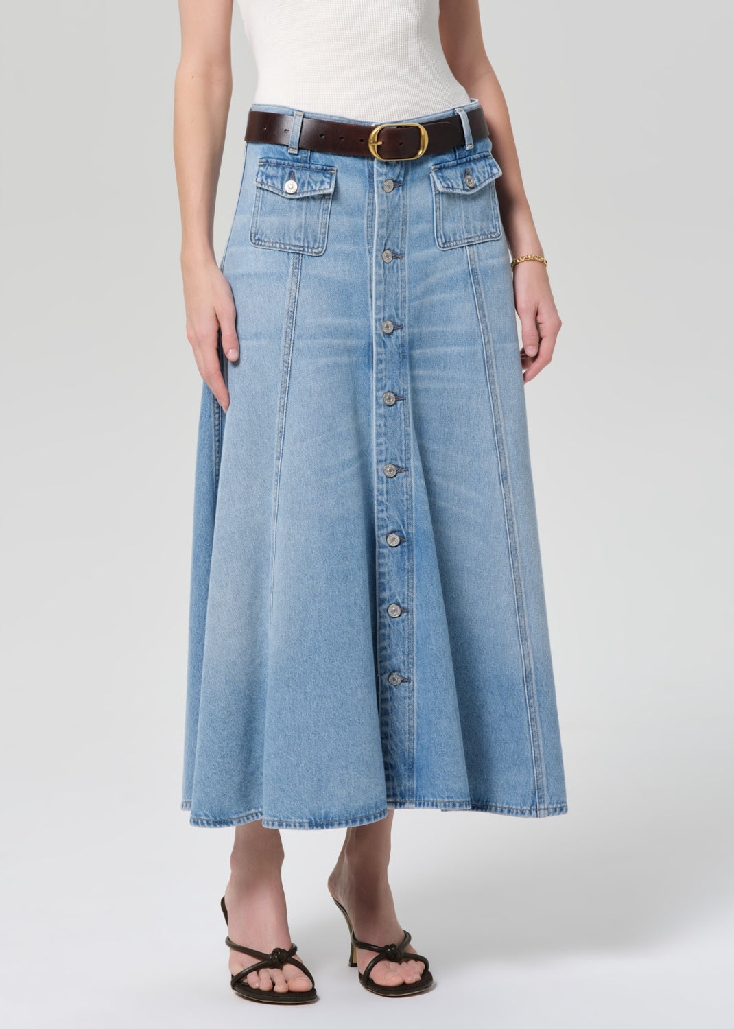 Person wearing a long denim skirt with a plain background
