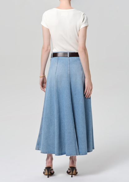 Person wearing a white top and blue denim skirt on a plain background