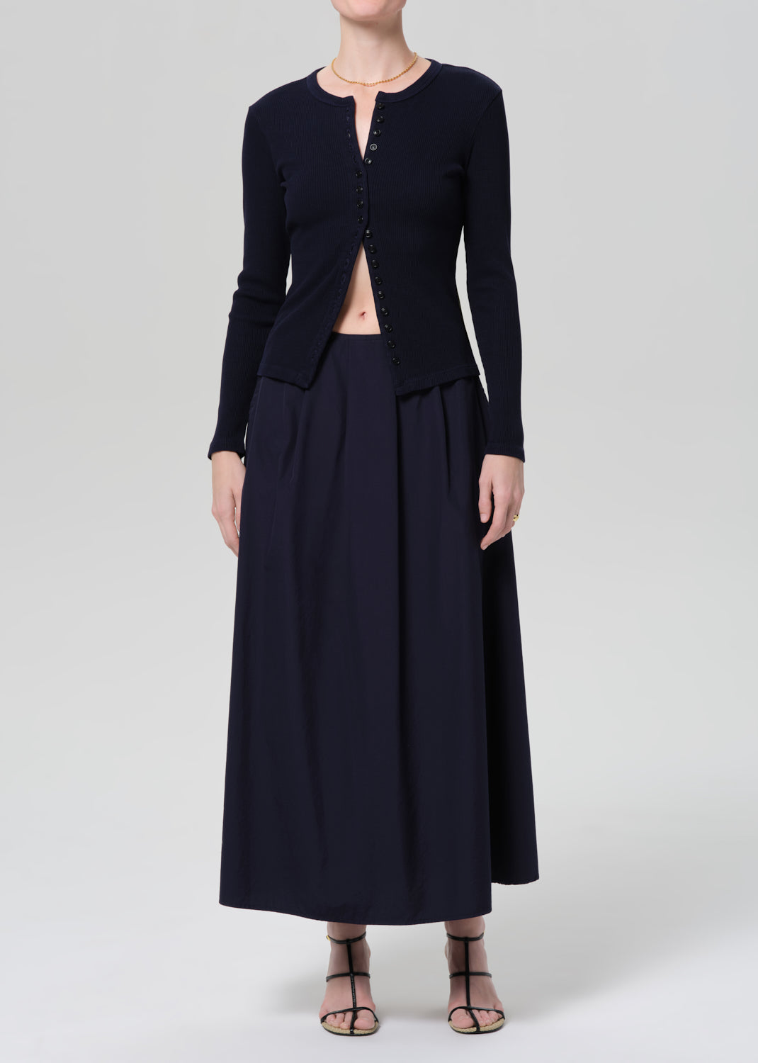 Person wearing a navy cardigan and long skirt on a grey background