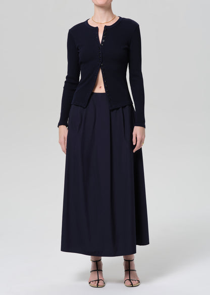 Person wearing a navy cardigan and long skirt on a grey background