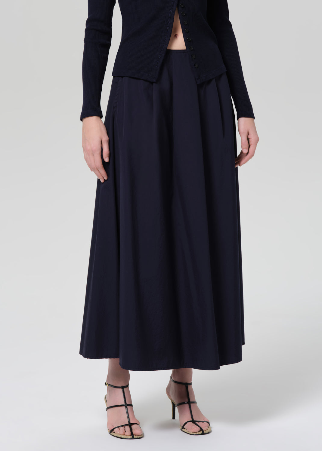 Person wearing a navy cardigan and long skirt on a grey background