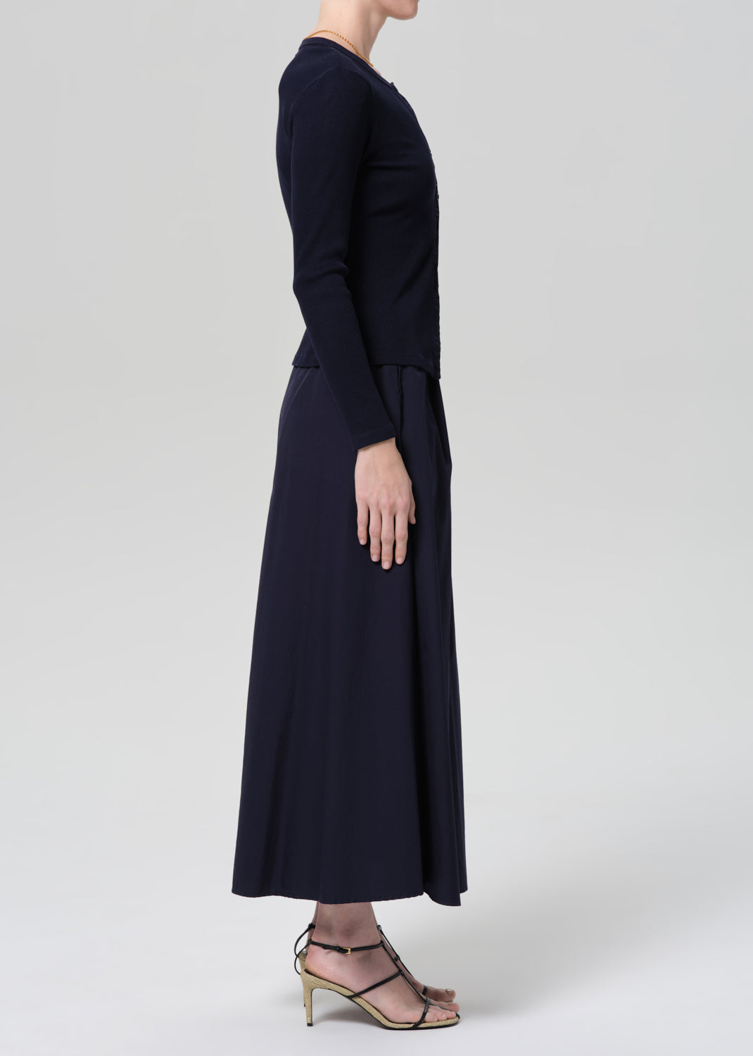 Person wearing a navy cardigan and long skirt on a grey background