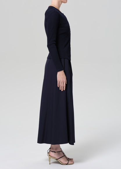 Person wearing a navy cardigan and long skirt on a grey background