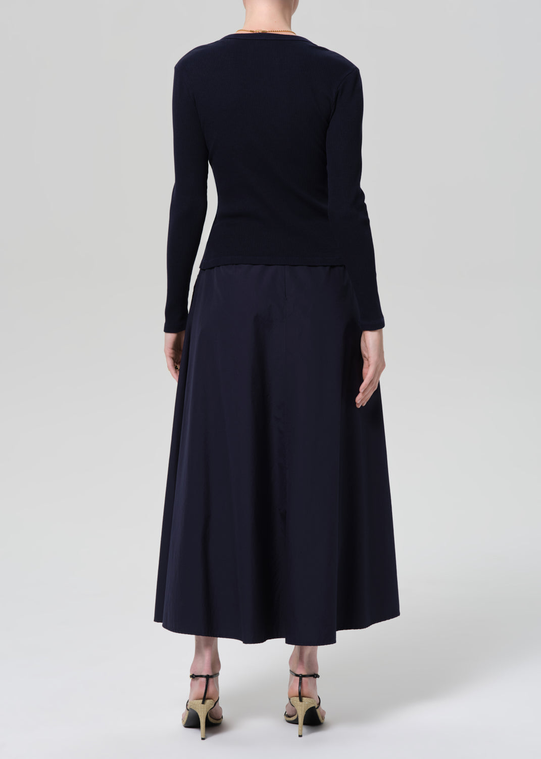 Person wearing a navy cardigan and long skirt on a grey background