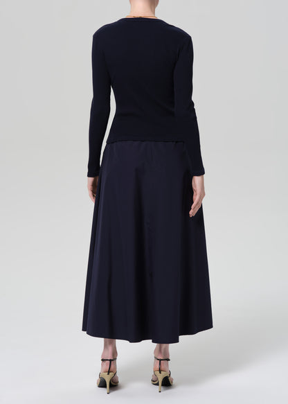 Person wearing a navy cardigan and long skirt on a grey background