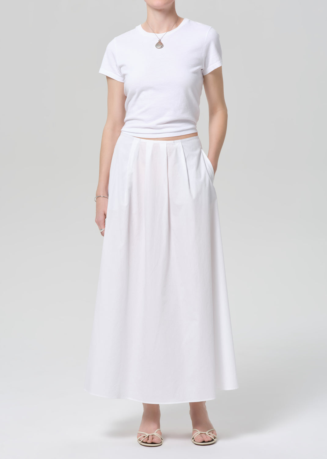 Person wearing a white t-shirt and long white skirt on a plain background