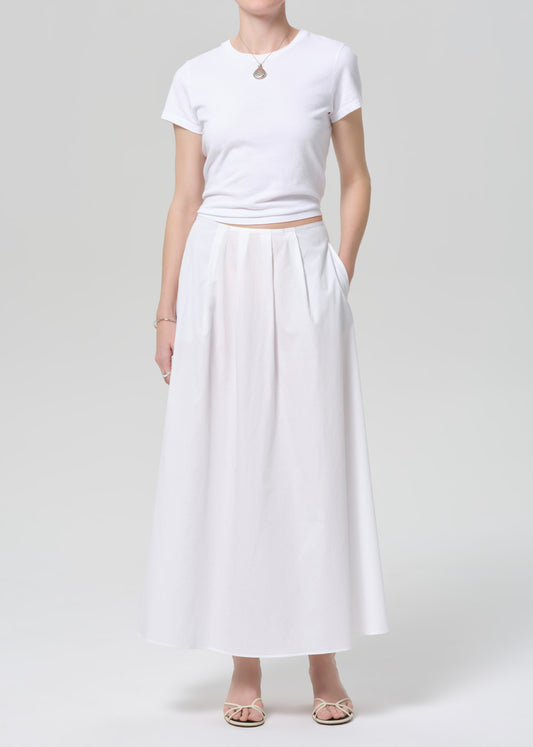 Person wearing a white t-shirt and long white skirt on a plain background