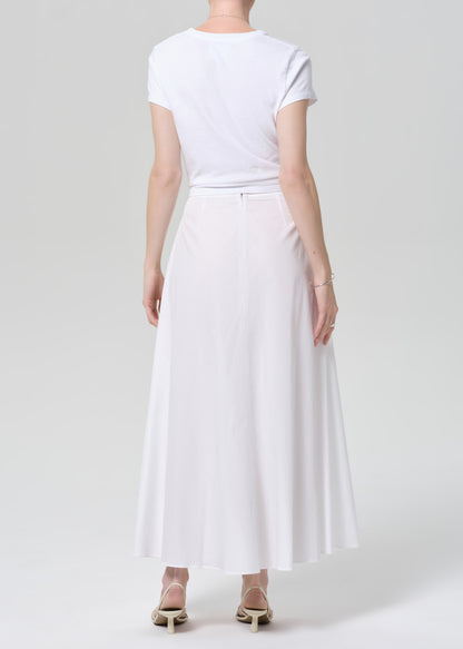 Person wearing a white t-shirt and long white skirt on a plain background
