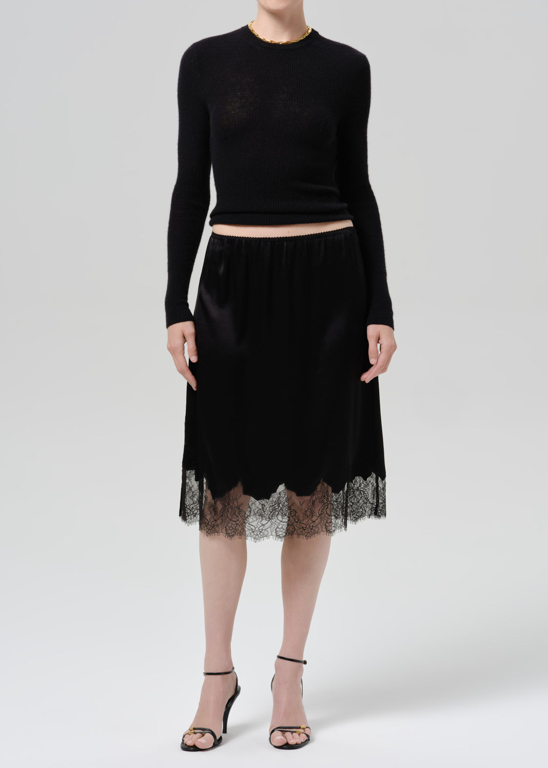 Person wearing black long sleeve top and black skirt on  a grey background