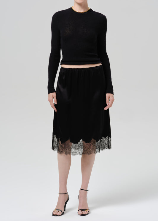 Person wearing black long sleeve top and black skirt on  a grey background