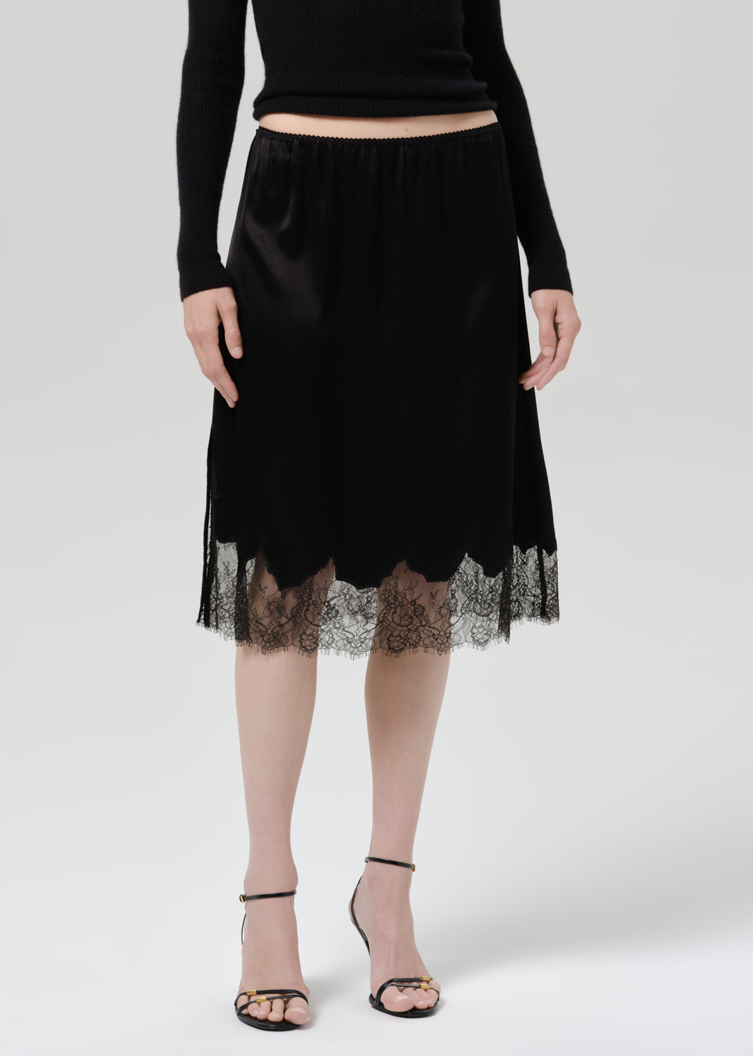 Person wearing black skirt and heels on a grey background