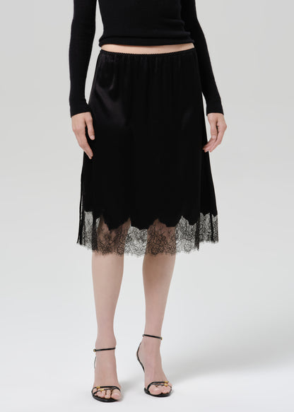 Person wearing black skirt and heels on a grey background