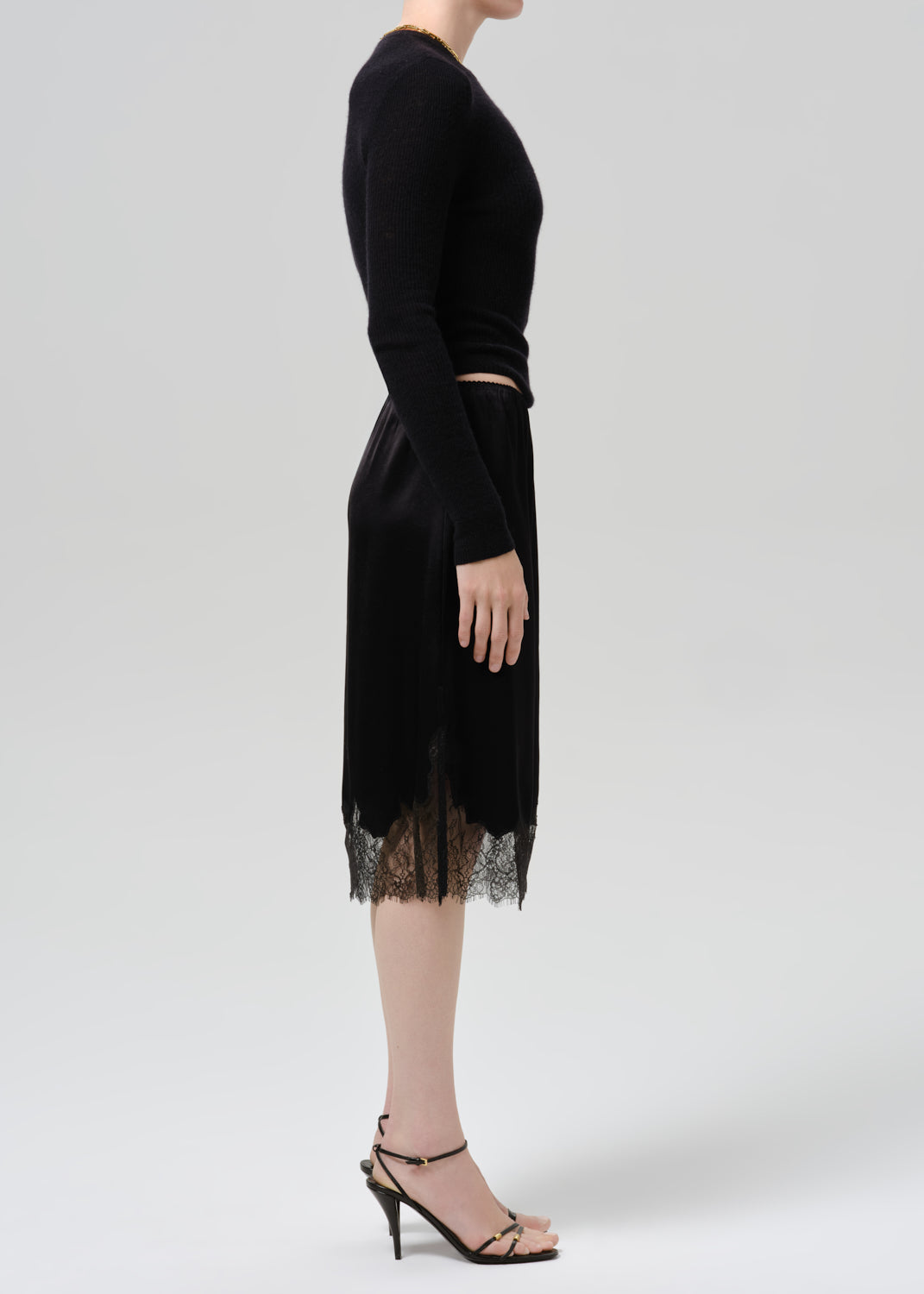 Person wearing black long sleeve top and black skirt on  a grey background
