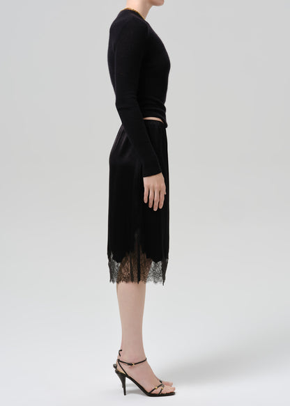 Person wearing black long sleeve top and black skirt on  a grey background