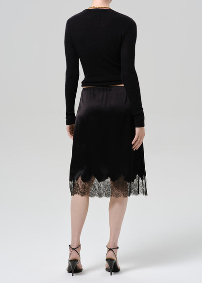 Person wearing black long sleeve top and black skirt on  a grey background