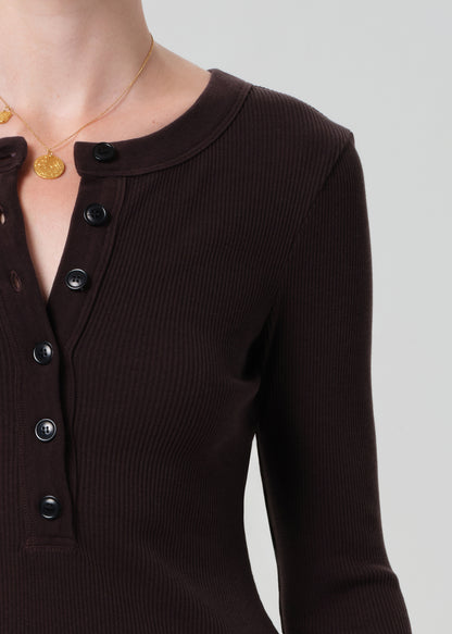 Person wearing a brown long-sleeve dress on a grey background