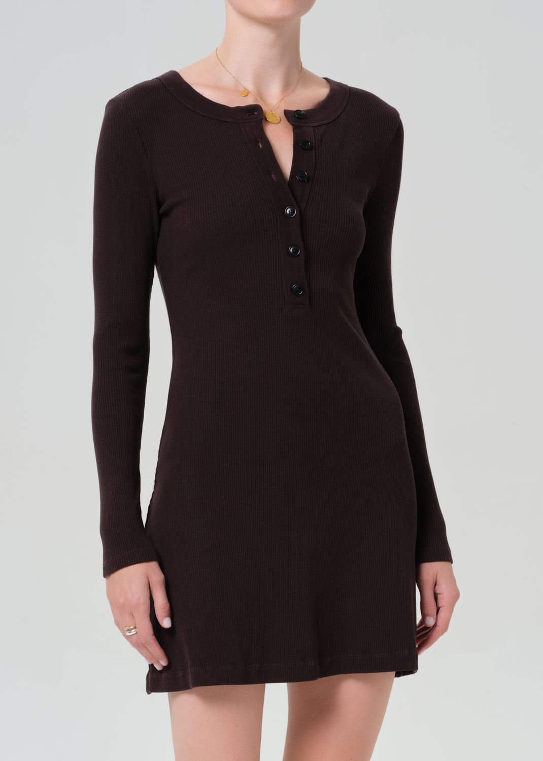 Person wearing a brown long-sleeve dress on a grey background