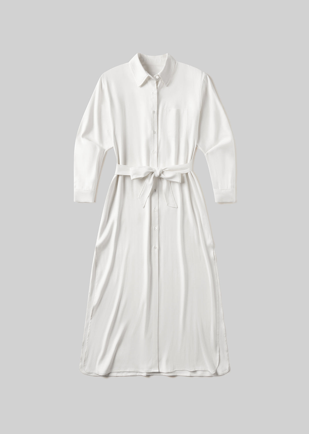 White long sleeve midi shirt dress with a pointed collar, front button closure, single chest pocket, and self-tie waist belt, front flat lay view on a grey background.