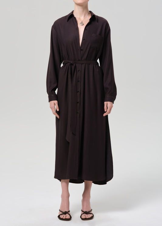 Person wearing a black dress with a belt on a grey background