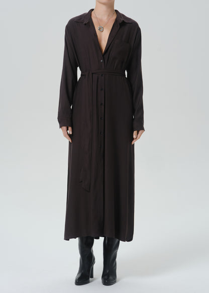 A model wearing a dark brown long-sleeve midi shirt dress with a tie waist belt, paired with black knee-high boots, against a grey background.