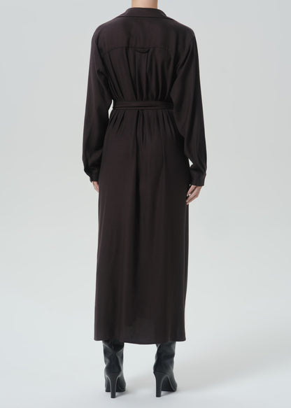 A model viewed from the back wearing a long-sleeved, dark brown midi shirt dress with a matching waist belt, paired with black pointed-toe heeled boots against a grey background.