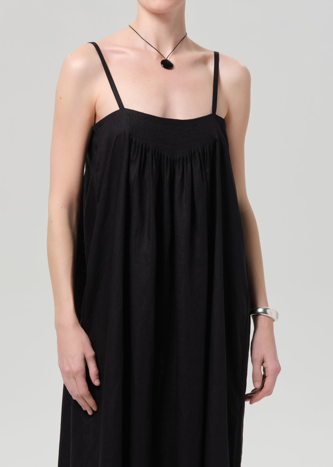 Person wearing a black linen dress on a grey background