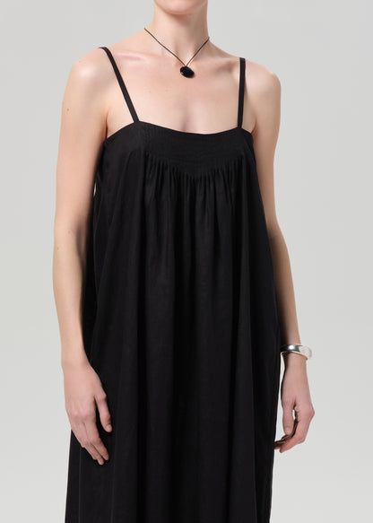 Person wearing a black linen dress on a grey background