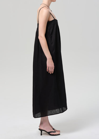 Person wearing a black linen dress on a grey background