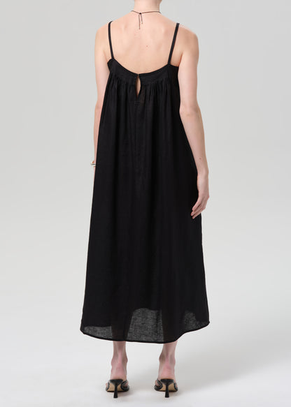 Person wearing a black linen dress on a grey background