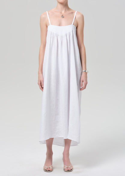 Woman wearing a white slip linen dress on a plain background