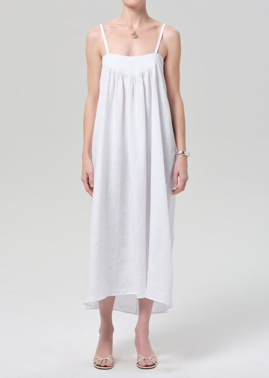 Woman wearing a white slip linen dress on a plain background