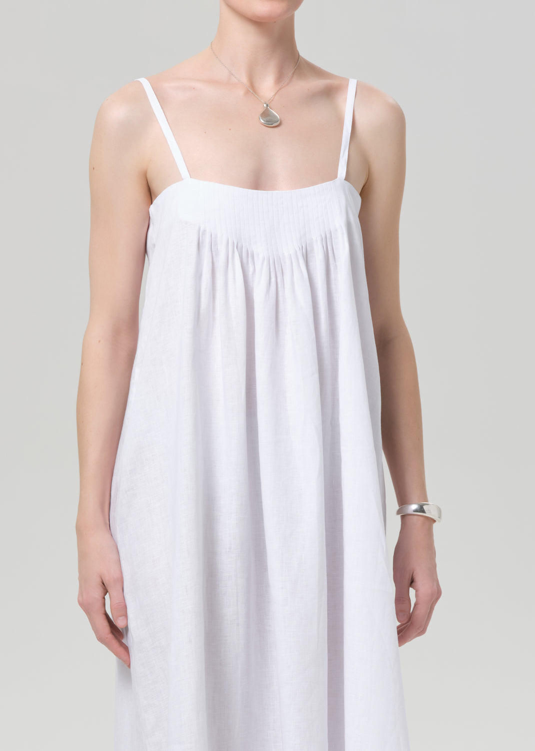 Woman wearing a white slip linen dress on a plain background