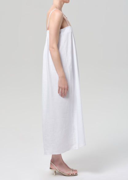 Woman wearing a white slip linen dress on a plain background