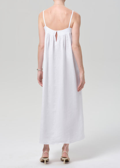 Woman wearing a white slip linen dress on a plain background