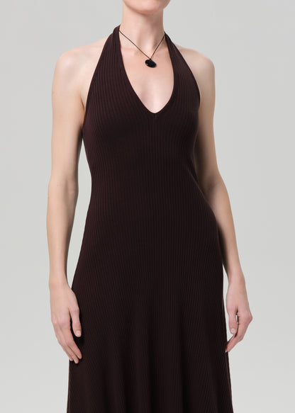 Woman wearing a brown halter neck dress on a plain background