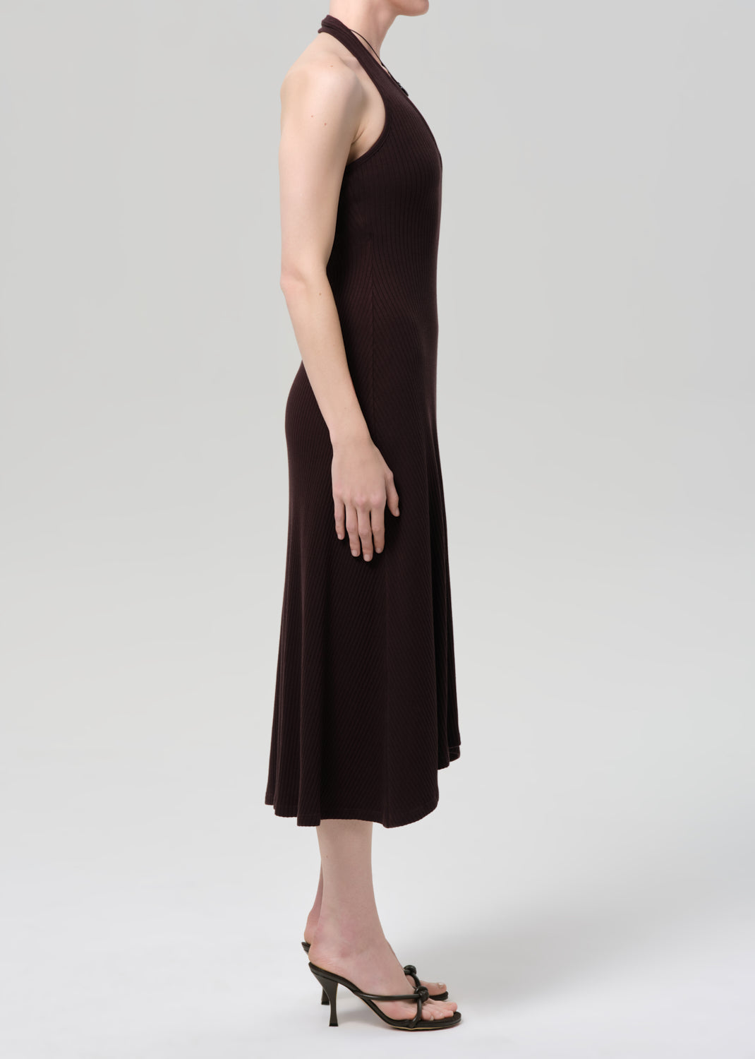 Woman wearing a brown halter neck dress on a plain background
