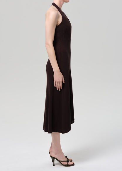Woman wearing a brown halter neck dress on a plain background