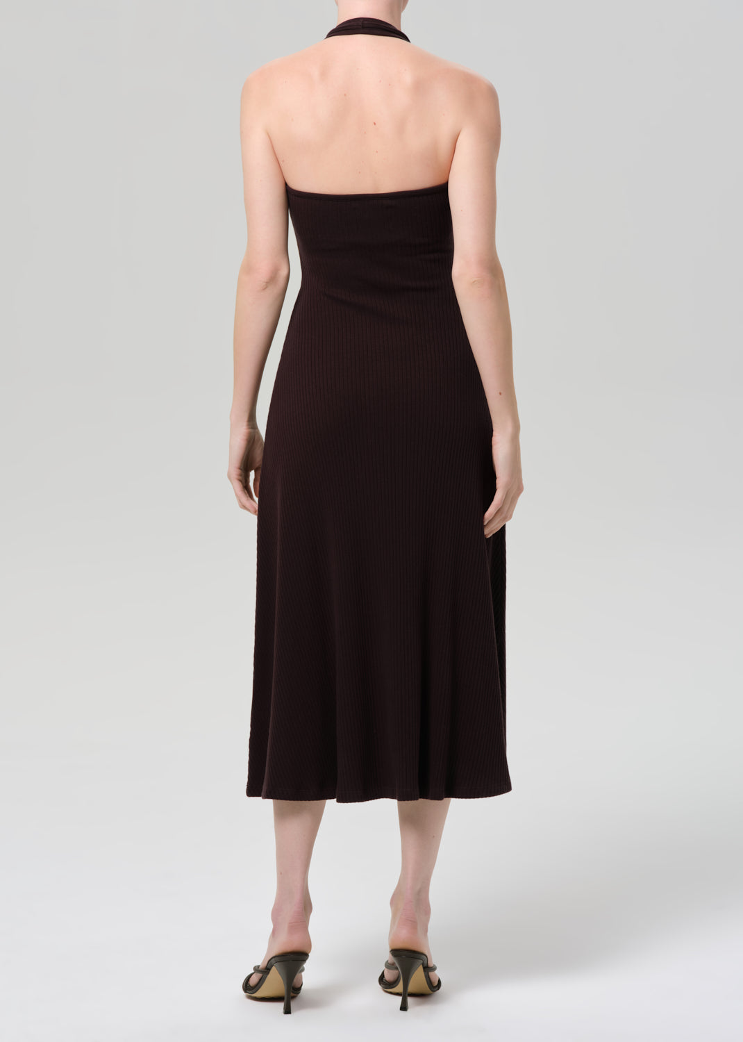 Woman wearing a brown halter neck dress on a plain background