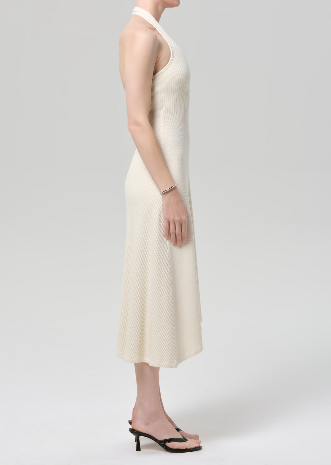 Woman wearing a cream halter neck dress on a plain background